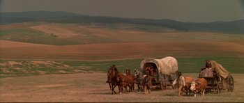 Movie still from “Ravenous” (1999), directed by Antonia Bird – A group of horses are pulling a covered wagon; Extreme Wide shot, High angle
