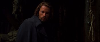 Movie still from “Ravenous” (1999), directed by Antonia Bird – A man with long brown hair wearing a black coat; Close Up shot, Over the shoulder angle