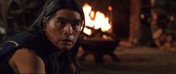 Movie still from “Ravenous” (1999), directed by Antonia Bird – A man with long black hair is in front of a fire; Close Up shot, Over the shoulder angle