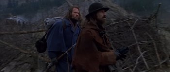 Movie still from “Ravenous” (1999), directed by Antonia Bird – Two men are walking through the woods while carrying backpacks; Medium shot, Low angle