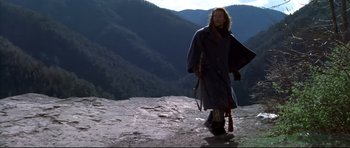 Movie still from “Ravenous” (1999), directed by Antonia Bird – A man in a long coat walking up a hill; Wide shot, Low angle