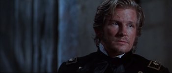 Movie still from “Ravenous” (1999), directed by Antonia Bird – A person wearing a suit and tie; Close Up shot, Over the shoulder angle