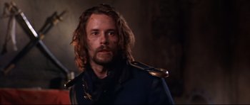 Movie still from “Ravenous” (1999), directed by Antonia Bird – A person with long hair and a beard; Close Up shot, Low angle