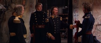 Movie still from “Ravenous” (1999), directed by Antonia Bird – A couple of men in military uniforms standing next to each other; Medium shot, Over the shoulder angle