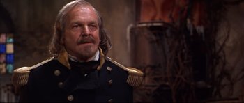 Movie still from “Ravenous” (1999), directed by Antonia Bird – An older man wearing a uniform and a hat; Close Up shot, Over the shoulder angle