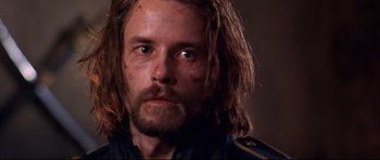 Movie still from “Ravenous” (1999), directed by Antonia Bird – A person with long hair and a beard; Close Up shot, Low angle