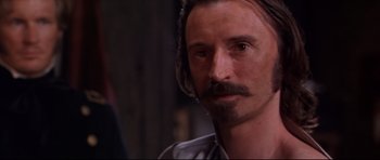 Movie still from “Ravenous” (1999), directed by Antonia Bird – A person with a mustache; Close Up shot, Over the shoulder angle