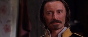 Movie still from “Ravenous” (1999), directed by Antonia Bird – A person with a beard and a mustache; Close Up shot, Over the shoulder angle