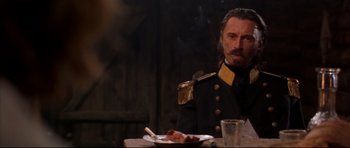 Movie still from “Ravenous” (1999), directed by Antonia Bird – A man sitting at a table with a plate in front of him; Close Up shot, Over the shoulder angle