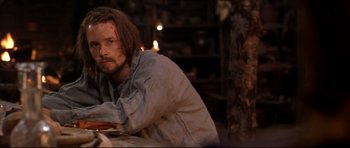 Movie still from “Ravenous” (1999), directed by Antonia Bird – A man sitting in front of a table with candles in the background; Close Up shot, Over the shoulder angle