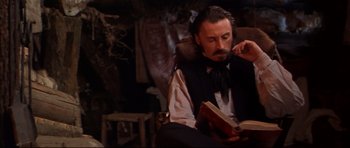 Movie still from “Ravenous” (1999), directed by Antonia Bird – A man sitting in a chair reading a book; Close Up shot, Low angle