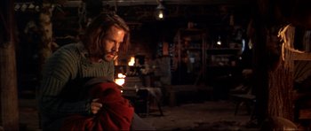 Movie still from “Ravenous” (1999), directed by Antonia Bird – A man holding a red blanket in a room; Medium shot, Over the shoulder angle