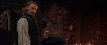 Movie still from “Ravenous” (1999), directed by Antonia Bird – A man standing in front of a large pot; Medium shot, Low angle