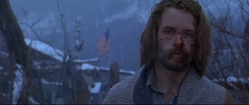 Movie still from “Ravenous” (1999), directed by Antonia Bird – A person with a flag in the background; Close Up shot, Low angle