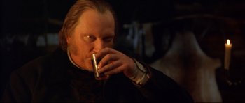 Movie still from “Ravenous” (1999), directed by Antonia Bird – A man drinking a drink while sitting down; Close Up shot, Over the shoulder angle