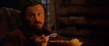 Movie still from “Ravenous” (1999), directed by Antonia Bird – A man sitting in front of a bowl of food; Close Up shot, Low angle