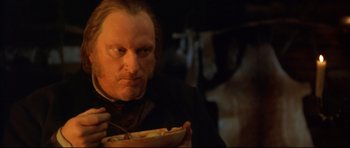 Movie still from “Ravenous” (1999), directed by Antonia Bird – A man eating a bowl of food while holding a spoon; Close Up shot, Over the shoulder angle