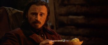 Movie still from “Ravenous” (1999), directed by Antonia Bird – A man sitting at a table with a knife in his hand; Close Up shot, Over the shoulder angle