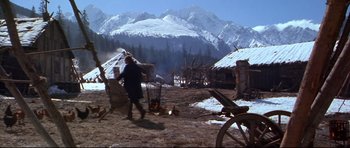 Movie still from “Ravenous” (1999), directed by Antonia Bird – A man is walking in the snow near a fire pit; Wide shot, High angle