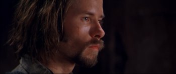 Movie still from “Ravenous” (1999), directed by Antonia Bird – A person with long hair and a beard; Close Up shot, Over the shoulder angle