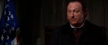 Movie still from “Ravenous” (1999), directed by Antonia Bird – A person sitting at a table; Close Up shot, Over the shoulder angle