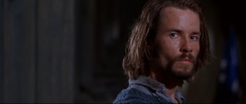 Movie still from “Ravenous” (1999), directed by Antonia Bird – A person with long hair and a beard; Close Up shot, Low angle