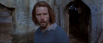 Movie still from “Ravenous” (1999), directed by Antonia Bird – A man with long brown hair wearing a sweater; Close Up shot, Low angle