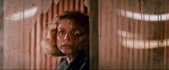 Movie still from “Razorback” (1984), directed by Russell Mulcahy – A person with curly hair near a wall; Close Up shot, Low angle