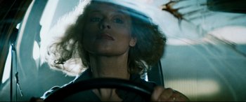 Movie still from “Razorback” (1984), directed by Russell Mulcahy – A woman driving a car in the rain; Close Up shot, Low angle