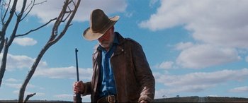 Movie still from “Razorback” (1984), directed by Russell Mulcahy – An older man in a cowboy hat and a leather jacket; Medium shot, Low angle