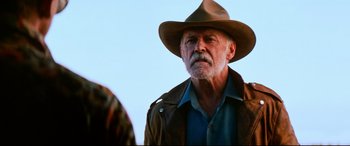 Movie still from “Razorback” (1984), directed by Russell Mulcahy – An older man wearing a brown hat and a brown jacket; Close Up shot, Low angle