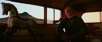 Movie still from “Razorback” (1984), directed by Russell Mulcahy – An older man sitting in front of an open window; Medium shot, Low angle
