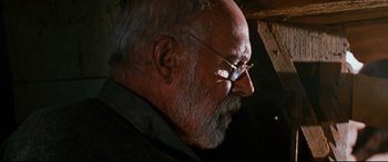 Movie still from “Razorback” (1984), directed by Russell Mulcahy – An old man with glasses is looking down; Close Up shot, Low angle