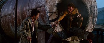 Movie still from “Razorback” (1984), directed by Russell Mulcahy – Two men are fighting in a warehouse; Medium shot, Low angle