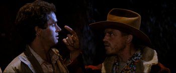 Movie still from “Razorback” (1984), directed by Russell Mulcahy – Two men in cowboy hats talking to each other; Close Up shot, Over the shoulder angle