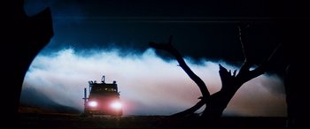 Movie still from “Razorback” (1984), directed by Russell Mulcahy – A truck is driving down the road at night; Extreme Wide shot, Low angle