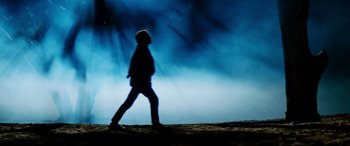 Movie still from “Razorback” (1984), directed by Russell Mulcahy – A person walking on a beach in front of a blue sky; Wide shot, Low angle