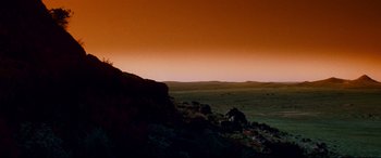 Movie still from “Razorback” (1984), directed by Russell Mulcahy – A view of a desert at sunset from a hill; Extreme Wide shot, Low angle