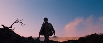 Movie still from “Razorback” (1984), directed by Russell Mulcahy – A man is walking in the desert at sunset; Wide shot, Low angle