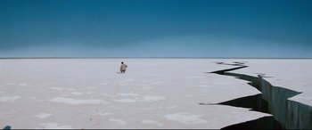Movie still from “Razorback” (1984), directed by Russell Mulcahy – A man standing on top of a snow covered field; Extreme Wide shot, High angle