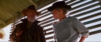 Movie still from “Razorback” (1984), directed by Russell Mulcahy – A man and a woman are standing next to each other; Medium shot, Low angle