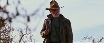 Movie still from “Razorback” (1984), directed by Russell Mulcahy – An older man wearing a brown hat and a leather jacket; Medium shot, Low angle