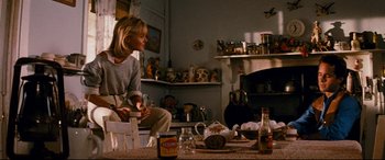 Movie still from “Razorback” (1984), directed by Russell Mulcahy – A woman sitting on a chair in a room; Medium shot, Over the shoulder angle