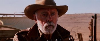 Movie still from “Razorback” (1984), directed by Russell Mulcahy – An old man with a beard wearing a cowboy hat; Close Up shot, Low angle
