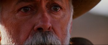 Movie still from “Razorback” (1984), directed by Russell Mulcahy – An older man with a beard and a mustache; Extreme Close Up shot, Low angle