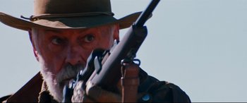 Movie still from “Razorback” (1984), directed by Russell Mulcahy – A person holding a rifle; Close Up shot, Low angle