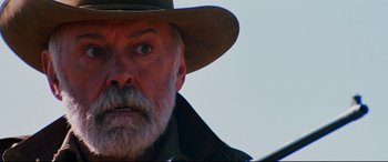 Movie still from “Razorback” (1984), directed by Russell Mulcahy – An old man with a beard wearing a cowboy hat; Close Up shot, Low angle