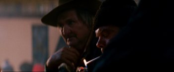 Movie still from “Razorback” (1984), directed by Russell Mulcahy – Two men sitting next to each other and one is smoking a cigarette; Close Up shot, Over the shoulder angle