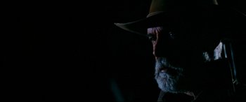 Movie still from “Razorback” (1984), directed by Russell Mulcahy – An old man with a beard wearing a brown hat; Close Up shot, Over the shoulder angle