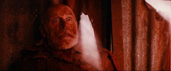 Movie still from “Razorback” (1984), directed by Russell Mulcahy – An old man is looking at the camera with an evil look on his face; Close Up shot, Low angle